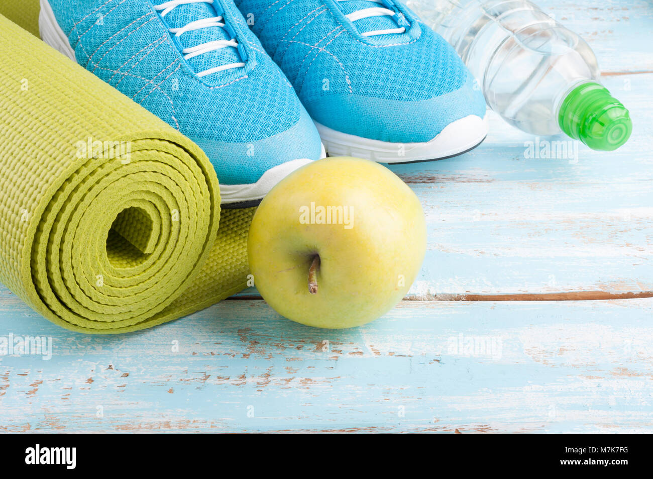 Yoga Matte, Sportschuhe, Apple, Flasche Wasser auf Blau Holz- Hintergrund. Konzept, gesunde Lebensweise, gesunde Ernährung, Sport und Diät. Sport Equipment. Sel Stockfoto