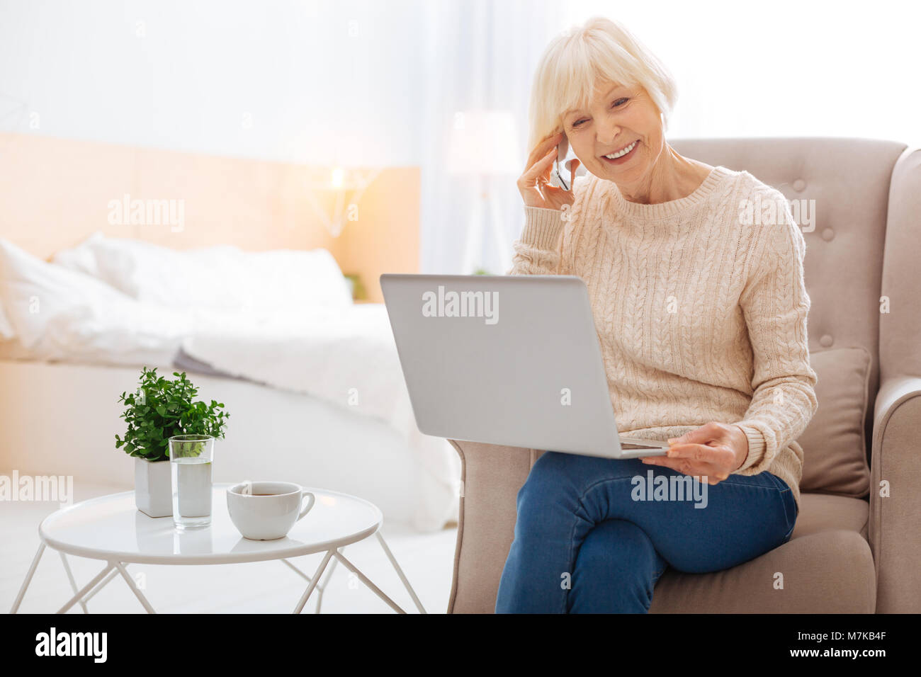 Emotional intelligente Rentner am Telefon zu sprechen, während sie mit einem Laptop Stockfoto