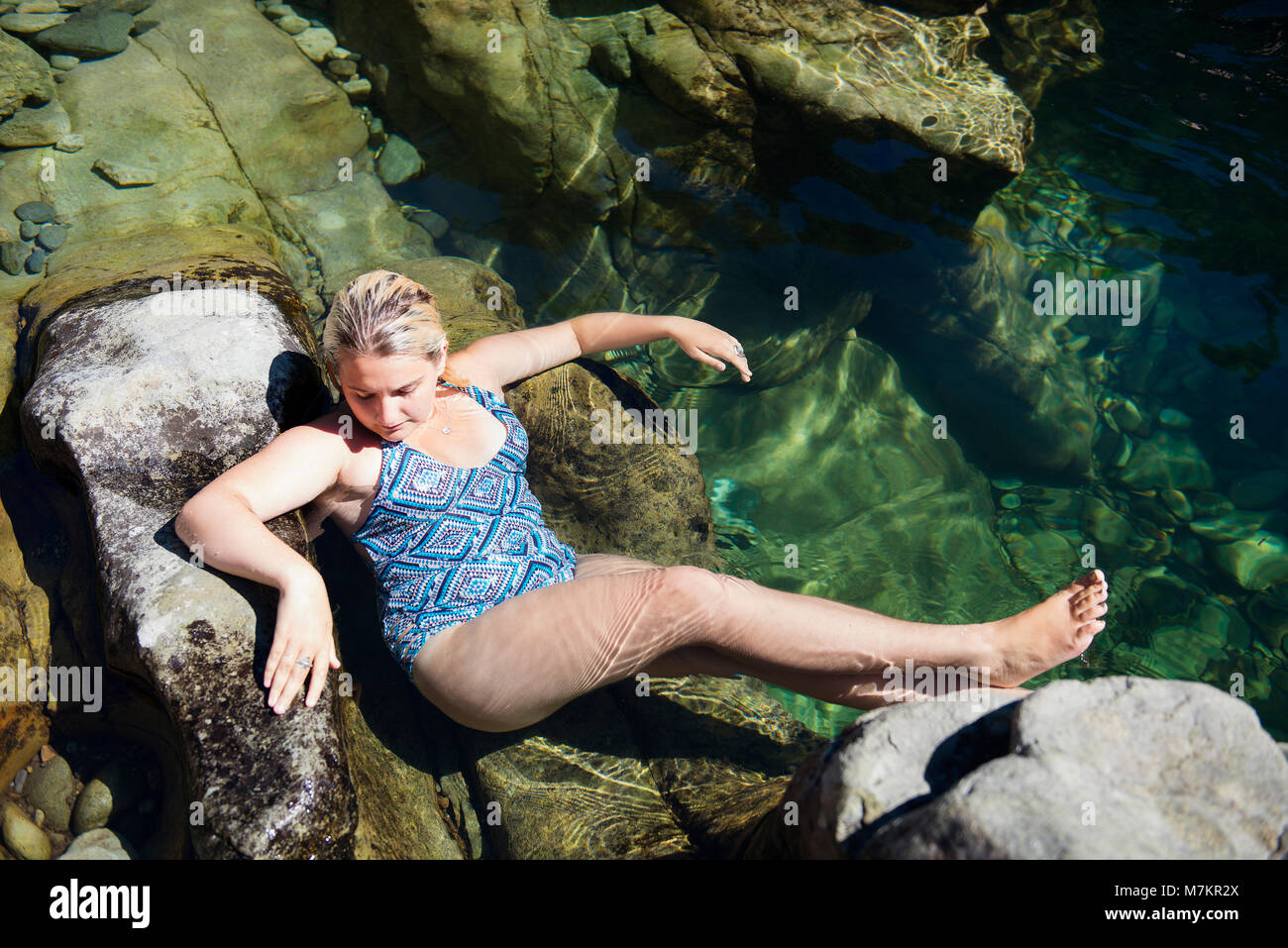 Eine junge Frau, die sich auf den Felsen an einem der drei Pools schwimmen Loch in Oregon. Stockfoto