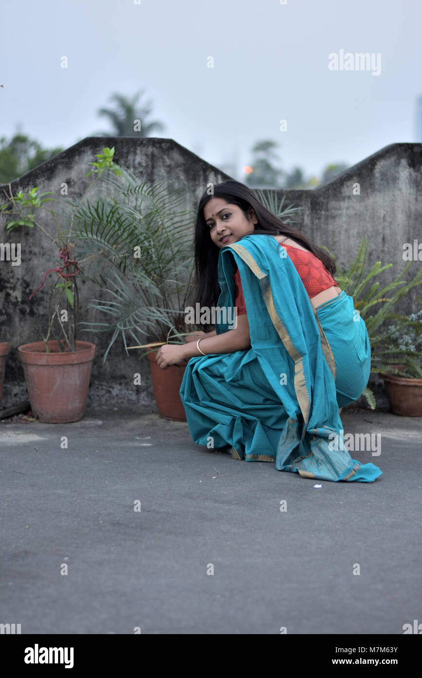 Schöne Bengali Dame kümmert sich um die Pflanzen auf dem Dach im Freien Stockfoto