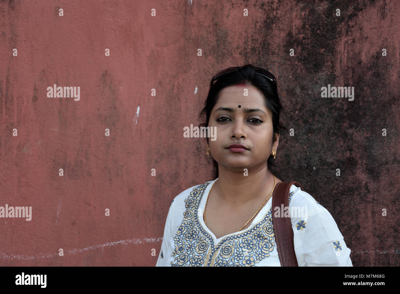 Bengali Dame steht vor einem roten vintage Wall Stockfoto