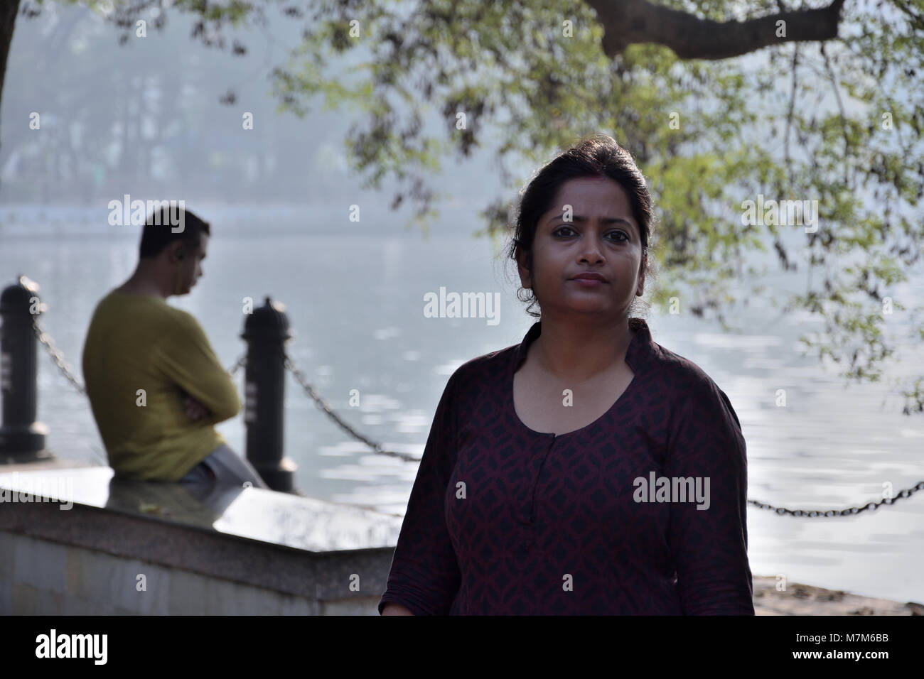 Bengali stehendes Mädchen im Park vor einem See Stockfoto