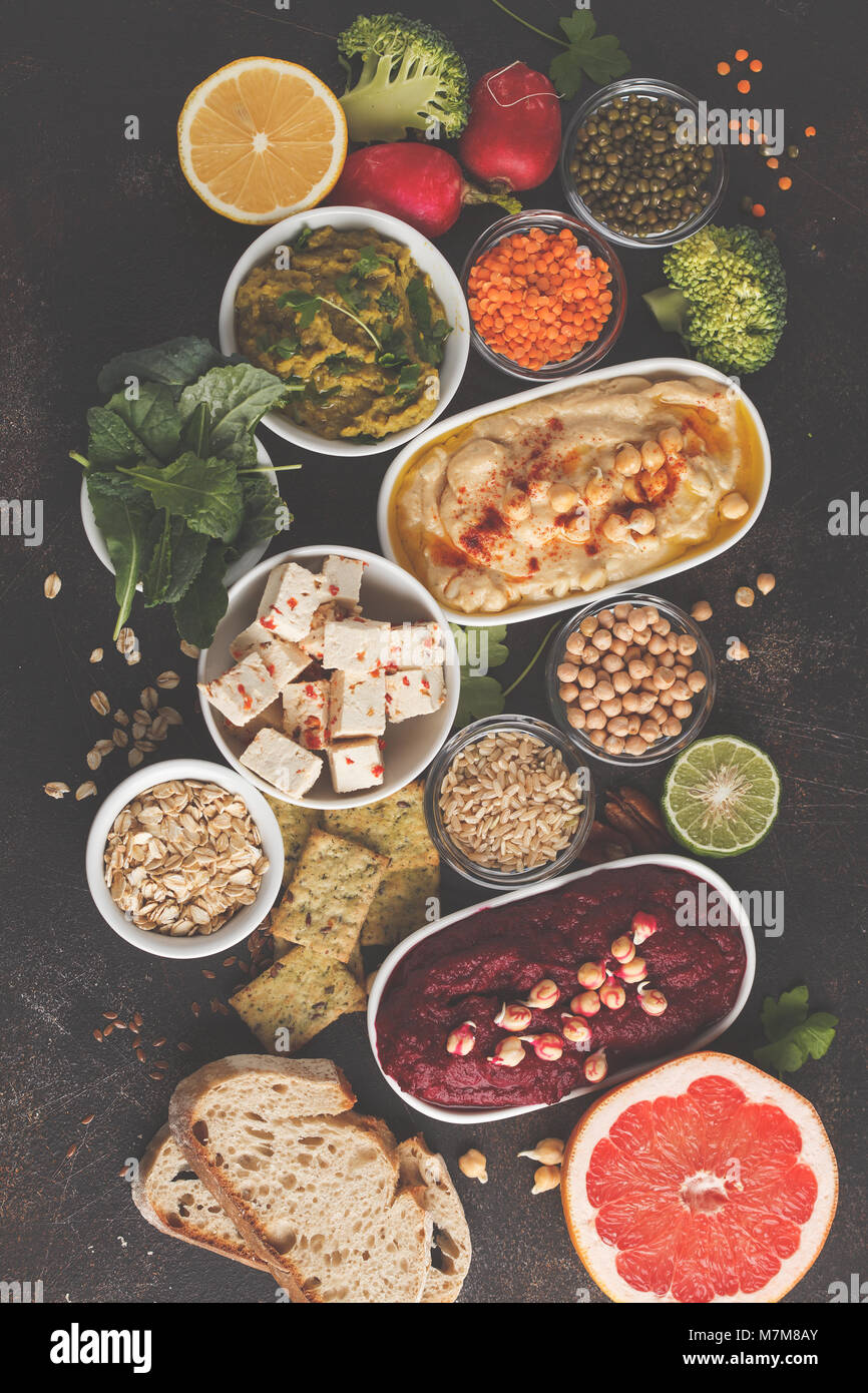 Veganes essen Hintergrund. Vegetarische Snacks: hummus Hummus, rote Beete, Erbsen dip, Gemüse, Tofu. Ansicht von oben, dunklen Hintergrund, kopieren. Stockfoto