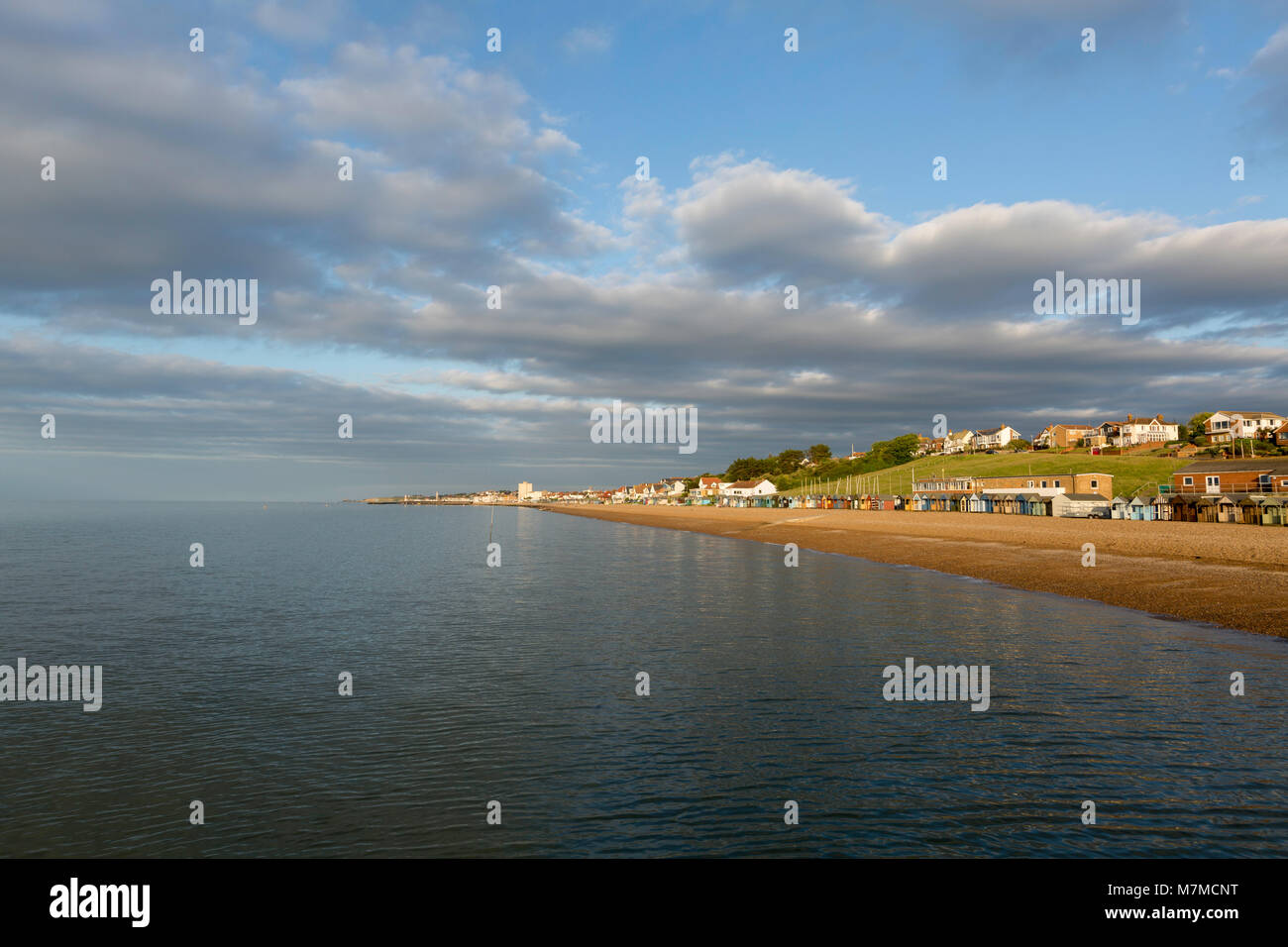 Anzeigen von Hampton Pier nach Herne Bay an der nördlichen Küste von Kent während der dramatischen Licht. Goldene Licht auf dem Kiesstrand und große weiße Wolken. Stockfoto