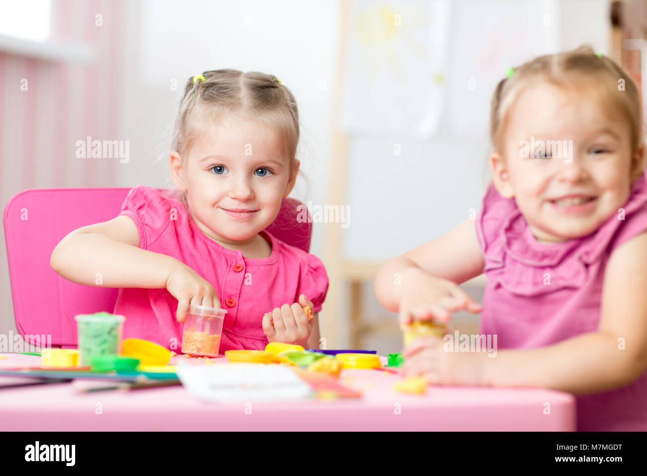 Zwei süße Vorschüler Schwestern Spaß zusammen mit bunte Knetmasse in eine Kindertagesstätte. Kreative Kinder Spritzgießen in Kindergärten zu Hause. Kinder spielen mit Plastilin oder Teig. Stockfoto