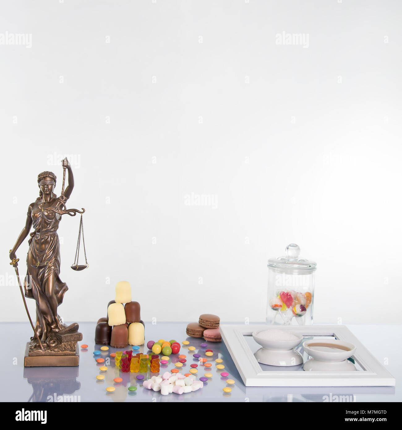 Justitia Statue auf dem Tisch mit vielen süßen Speisen Stockfoto
