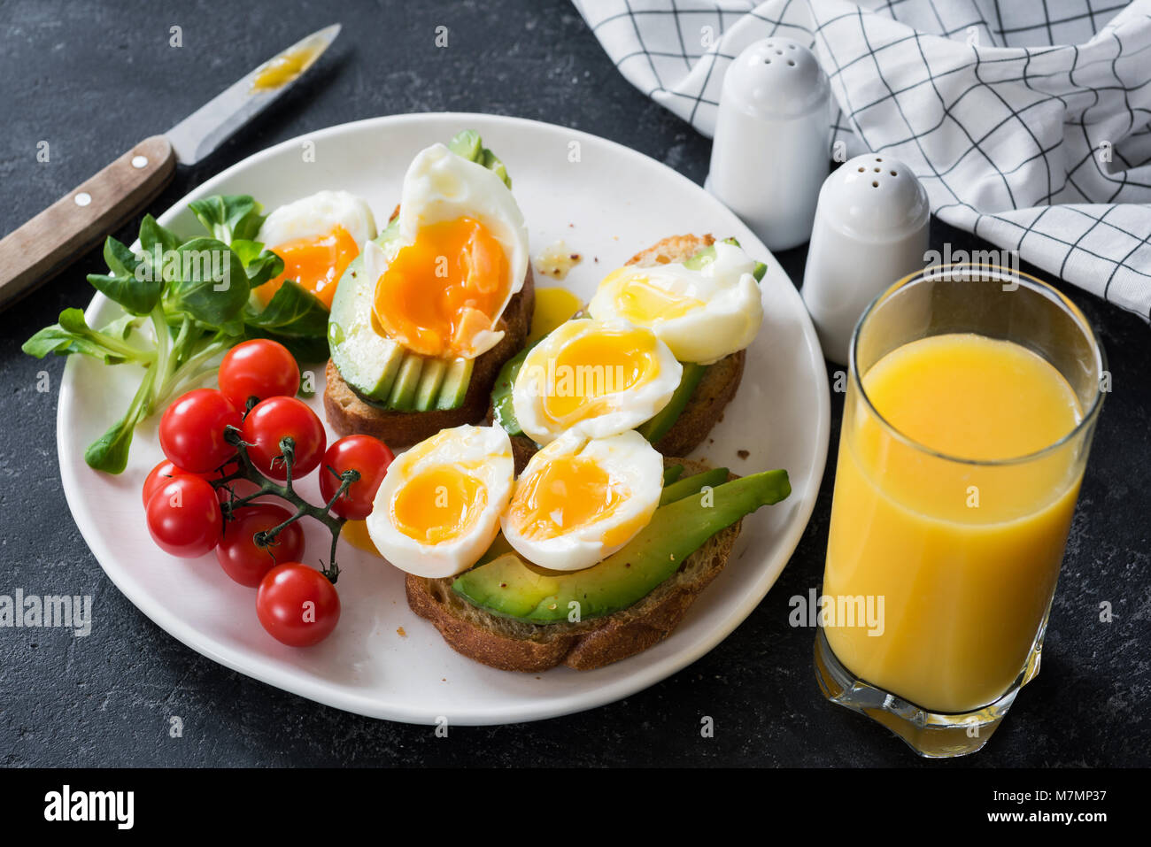 Avocado und pochiertem Ei Toast, Salat und Orangensaft auf Tisch aus ...