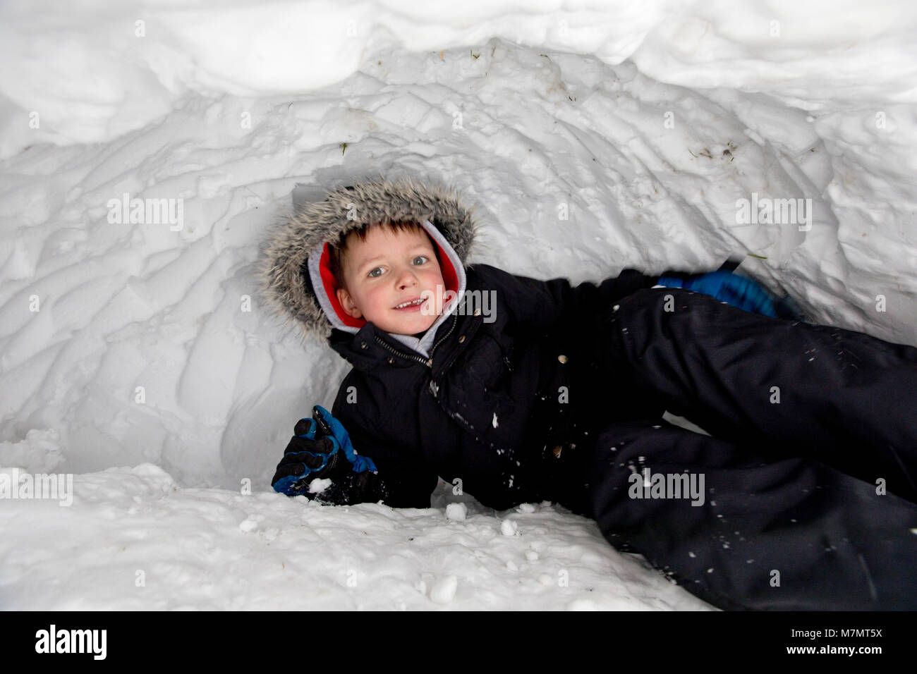 5 Jahre alter Junge spielt in seinem Iglu, Großbritannien Stockfoto