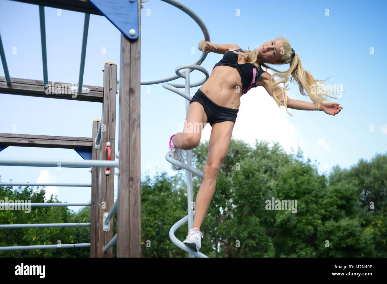 Schlanke junge Frau Sport im Park. Athletische blondes Mädchen in Fitness auf Natur und hängen an der Sportausrüstung Stockfoto