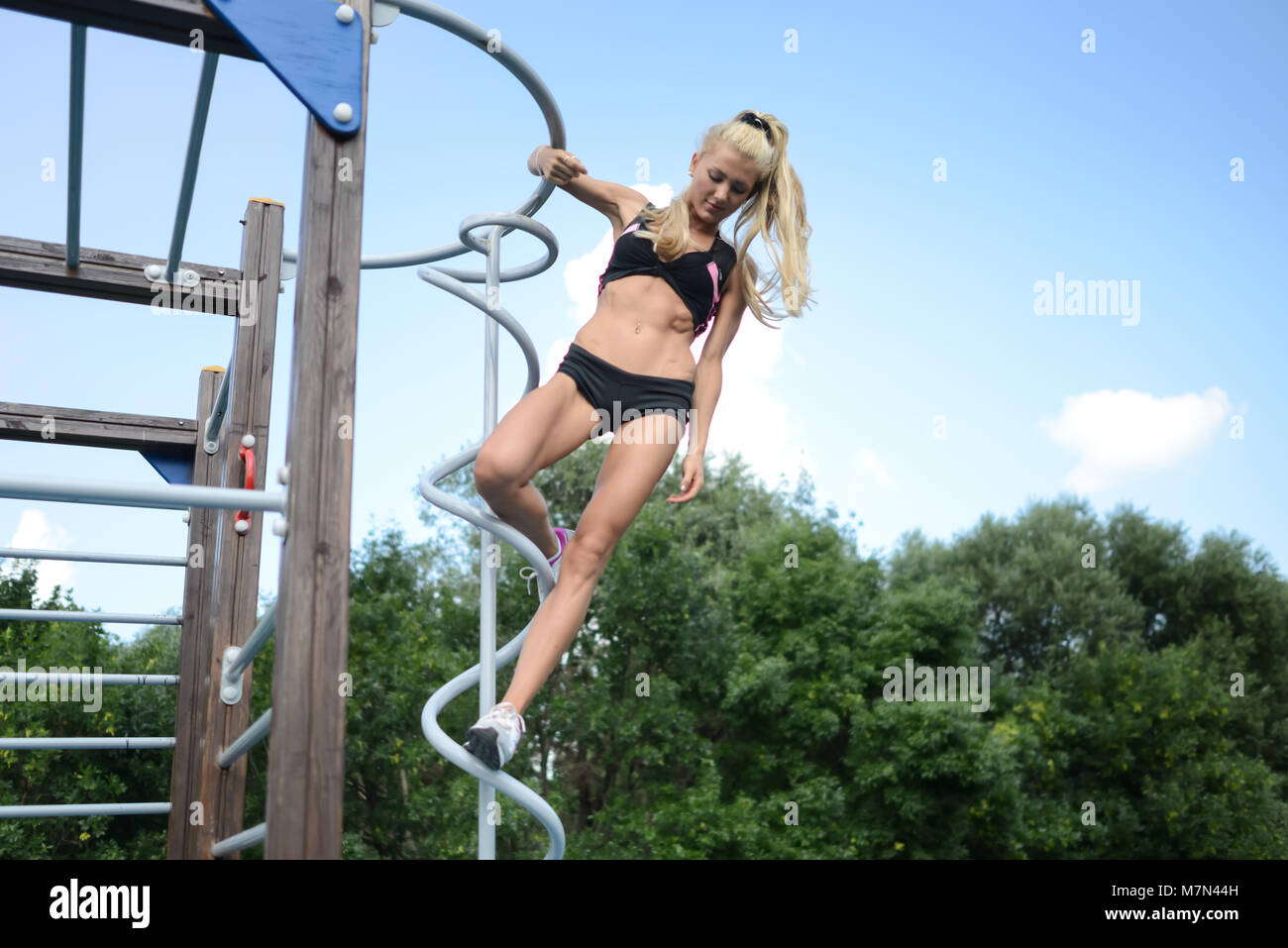 Athletische junge Frau Sport im Park. Schlanke blonde Mädchen mit Haar in Fitness engagiert. Attraktiven weiblichen hängen an Sportausrüstung Stockfoto