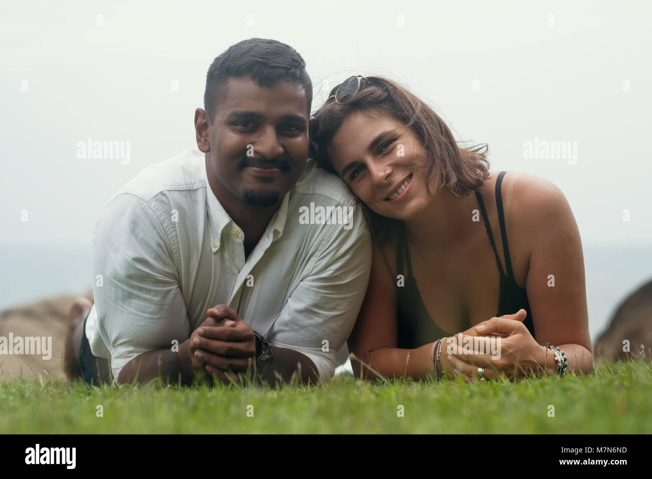 Junge romantische Mixed Race Paar im Park liegend auf grünem Gras. Stockfoto
