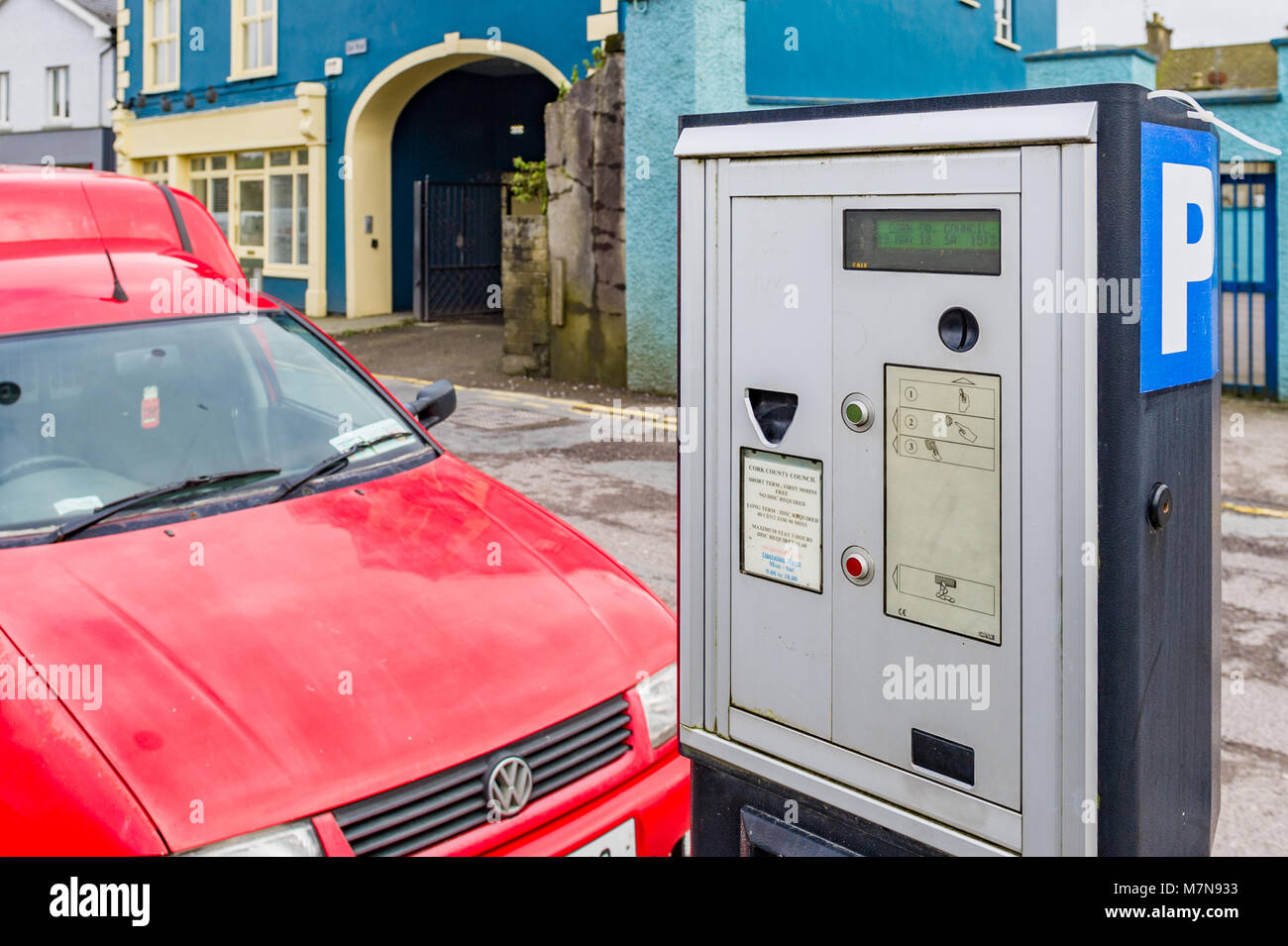 Roter VW-Transporter auf der Straße neben einem münzautomat Parkuhr in Bandon, County Cork, Irland geparkt. Stockfoto