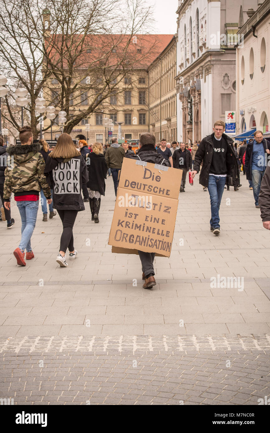 München, Germany-March 10,2018: ein Mann in der Münchner Fußgängerzone trägt ein handgeschriebenes Schild in deutscher Sprache protestieren gegen Korruption in deutscher Sprache Stockfoto