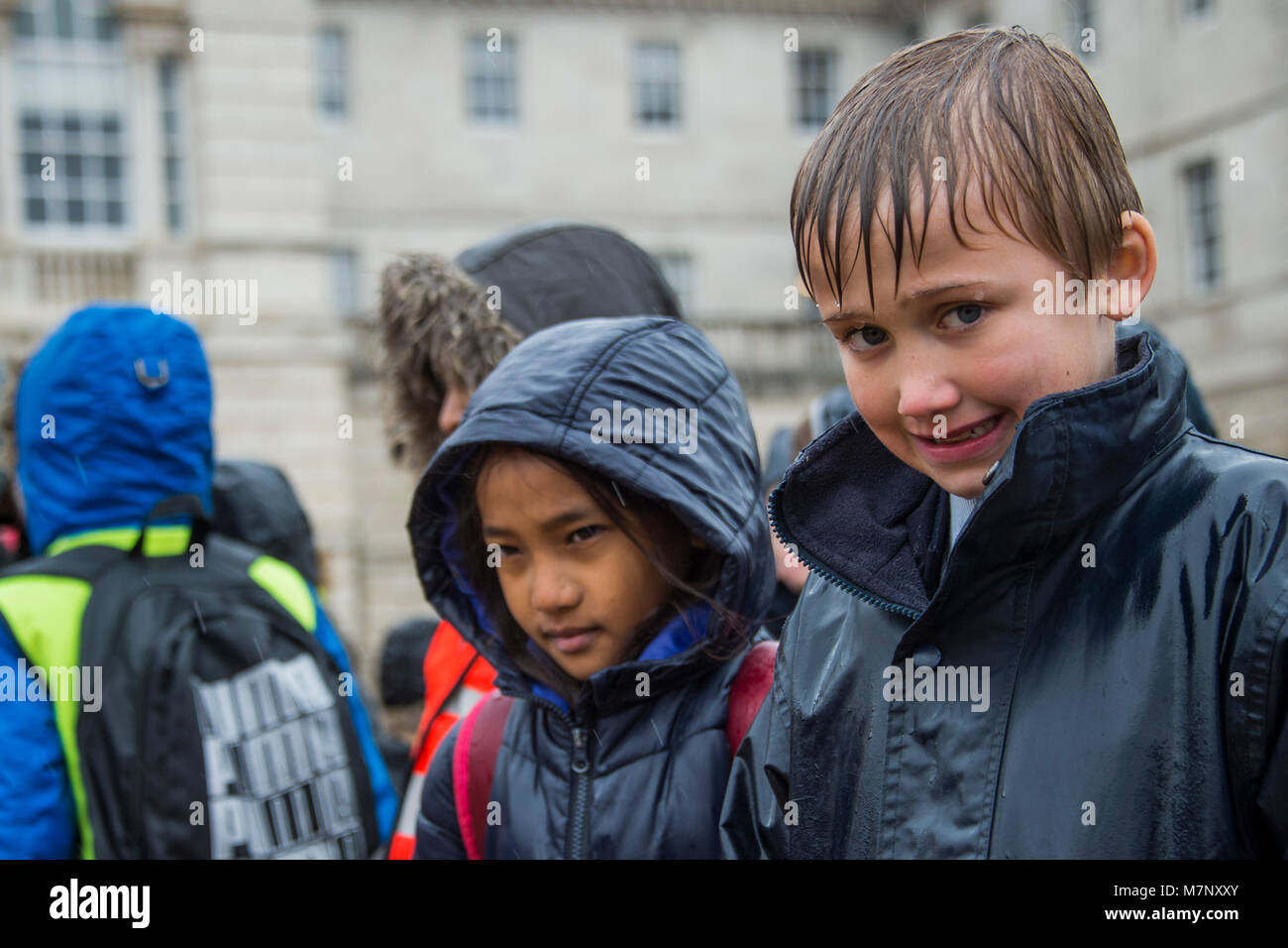 London, Großbritannien. 12. März, 2018. Der Regen fiel Dämpfung einige Geister - Die Band der Coldstream Guards begleitet 400 Mitglieder des Commonwealth Kinderchor in eine musikalische Feier des Commonwealth Tag 2018. Die Leistung, auf Horse Guards Parade, enthalten eine Weltpremiere einer neuen Zusammensetzung, "ein Freund", Ihrer Majestät der Königin (dedizierte und Markierung der Commonwealth Tagung der Regierungschefs (chogm) in London im April 2018 gehalten wird). Es wurde komponiert von großen Simon Haw MBE. Credit: Guy Bell/Alamy leben Nachrichten Stockfoto