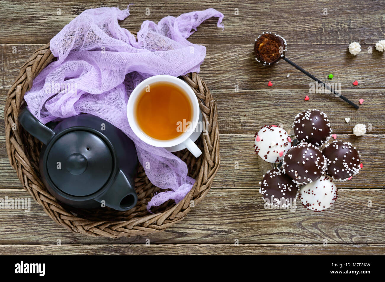 Kuchen knallt. Runde Süßigkeiten auf einem Stock in Schokolade Glasur. Eine Tasse Tee. Stockfoto