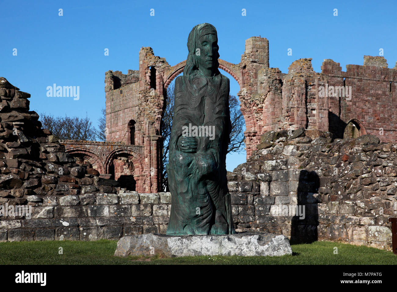 Die Statue des Heiligen Cuthbert von Fenwick Lawson vor der "Rainbow arch" an Lindisfarne Priory Kirche, die Heilige Insel. Stockfoto