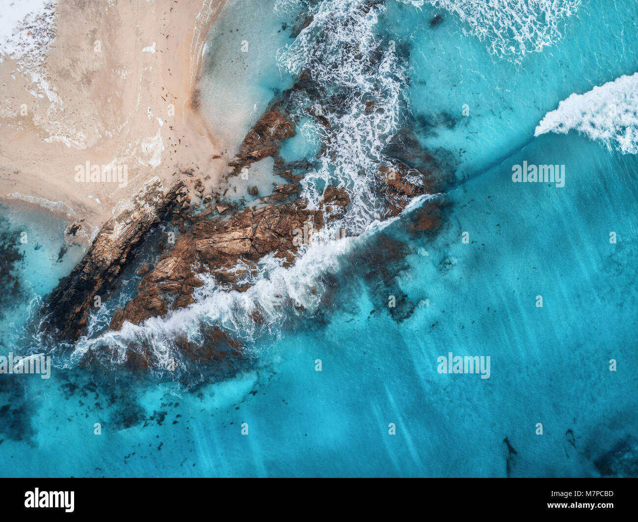 Luftaufnahme von Wellen, Felsen und transparenten Meer. Sommer Meereslandschaft mit Meer, Sandstrand, schöne Wellen, Felsen, blaues Wasser bei Sonnenuntergang. Blick von oben Stockfoto