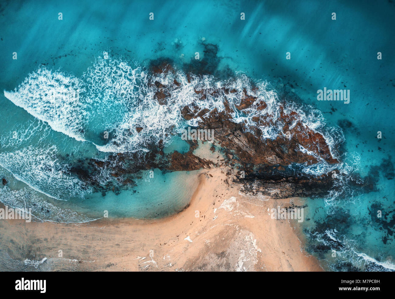 Luftaufnahme von Wellen, Felsen und transparenten Meer. Sommer Meereslandschaft mit Meer, Sandstrand, schöne Wellen, Felsen, blaues Wasser bei Sonnenuntergang. Blick von oben Stockfoto