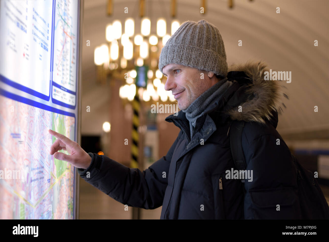 Reifer mann im winter Kleidung an einen Stadtplan in St. Petersburg der u-bahn suchen Stockfoto