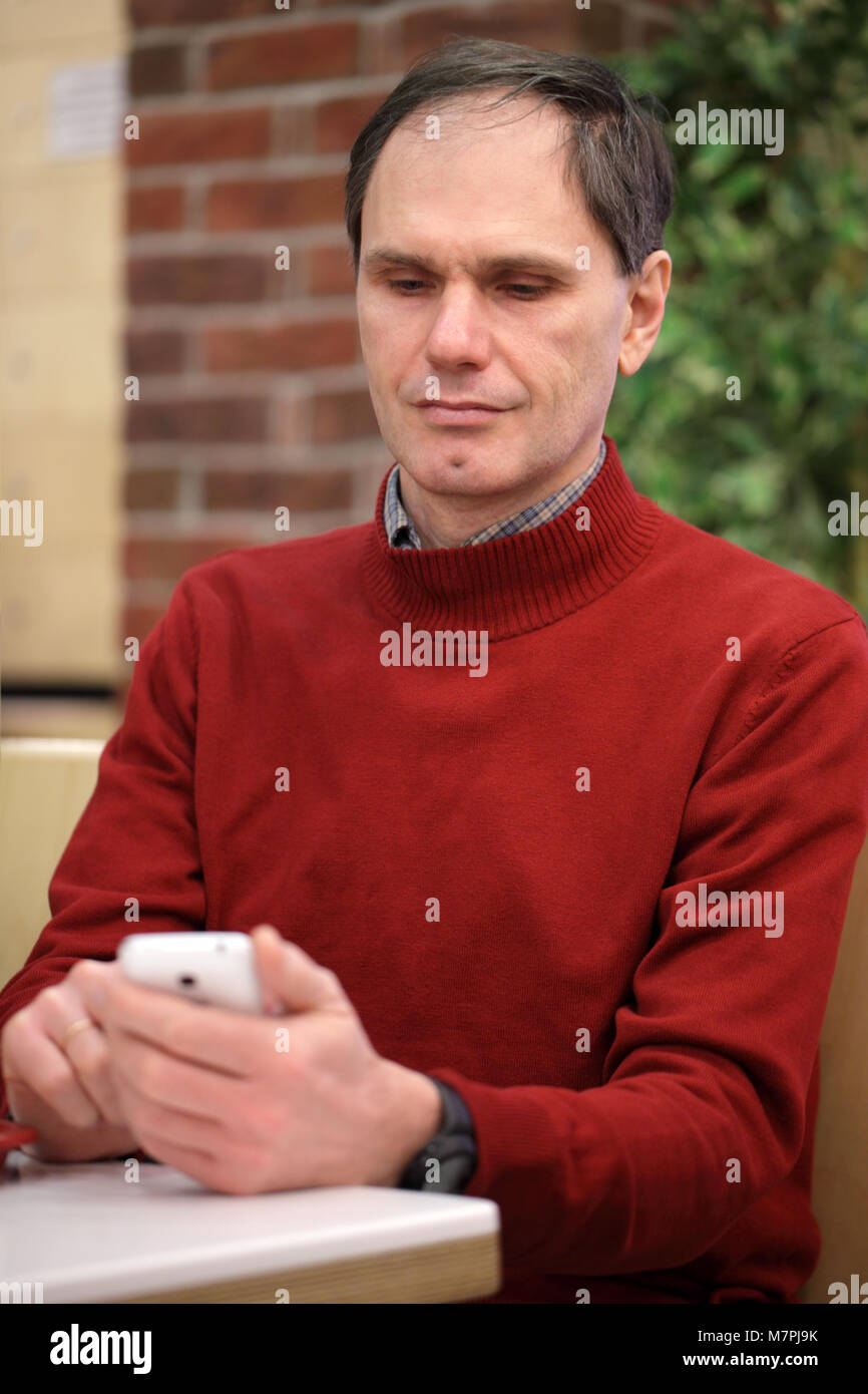 Reifer Mann sein Smartphone lesen in einem Cafe Stockfoto