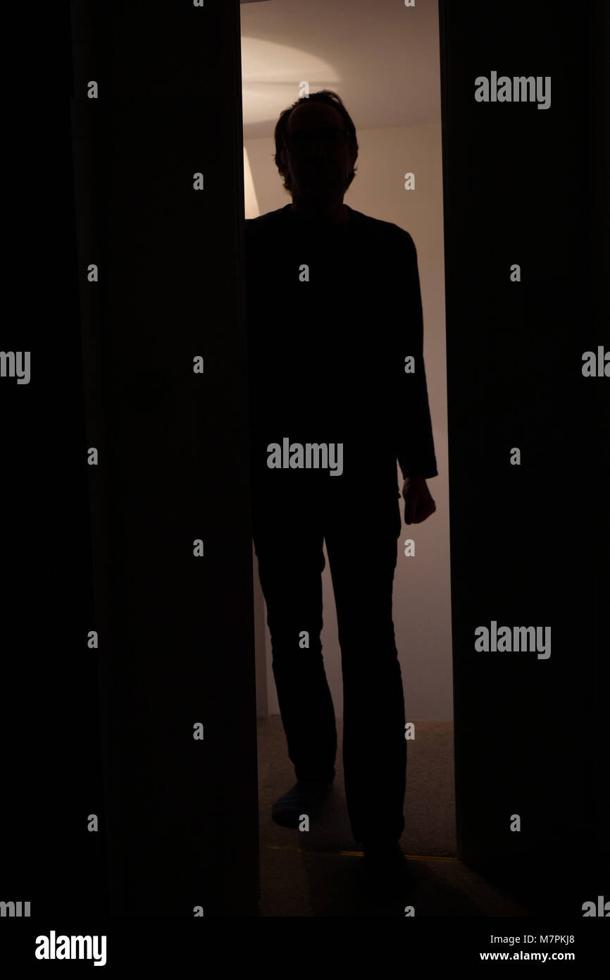 Hintergrundbeleuchtung der Mensch einen Raum betreten durch eine Tür von einem Flur suchen bedrohlich Stockfoto
