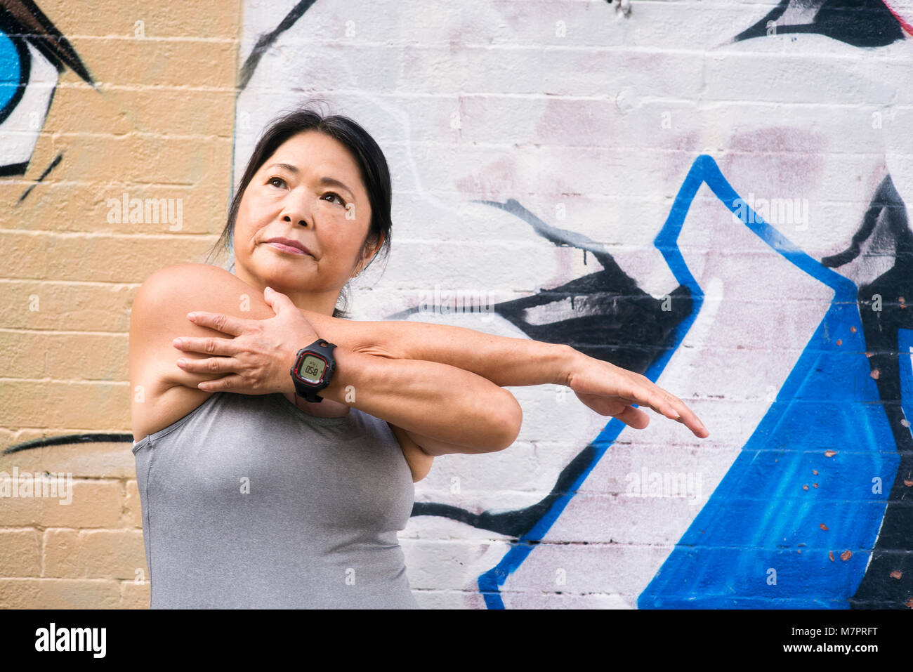 Eine Frau (65) Trägt ein Fitnessgerät, der sich in der Vorbereitung für ein Workout. Stockfoto