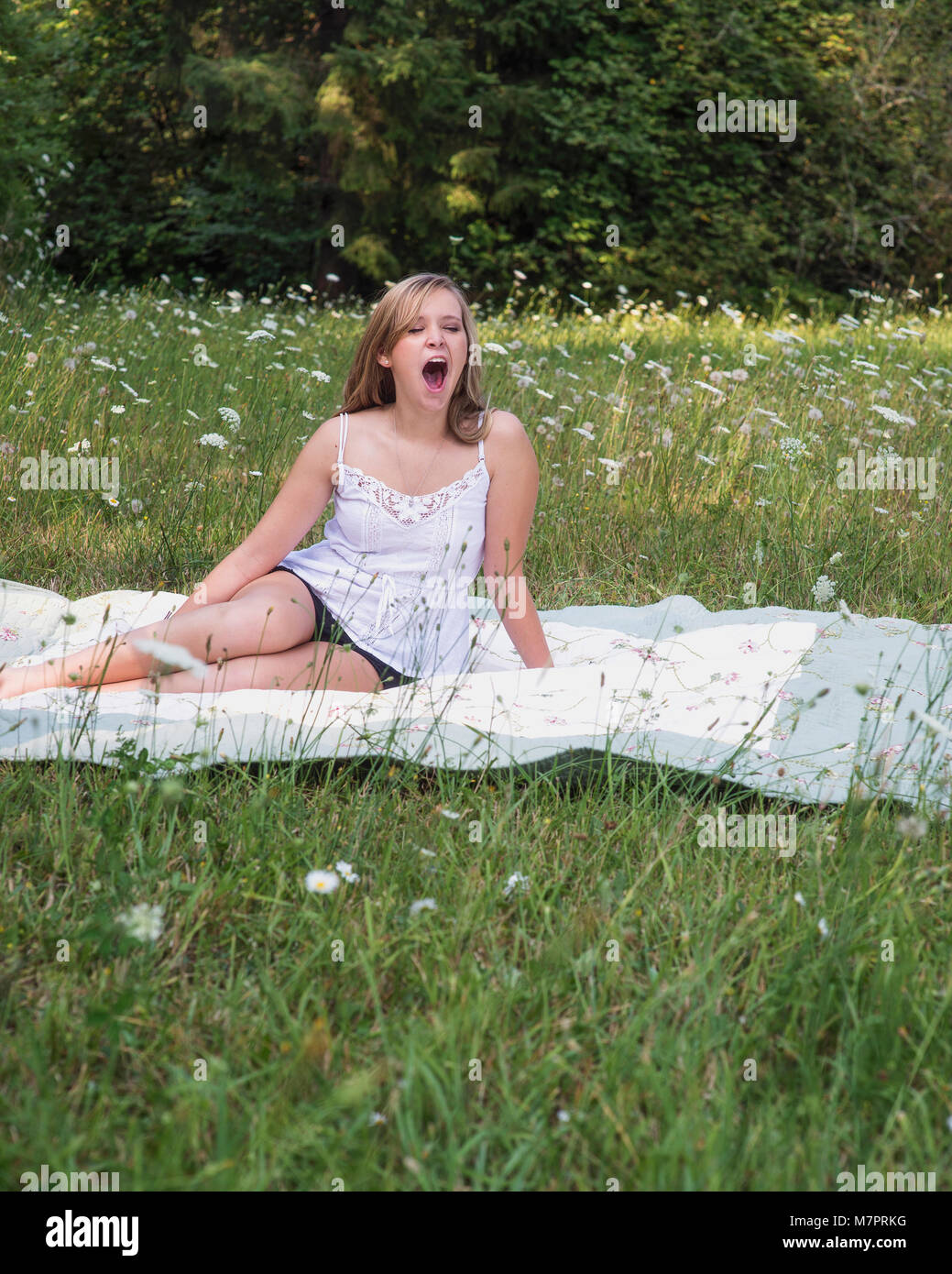 Eine junge Frau in einem Feld von Blumen Gähnen. Stockfoto