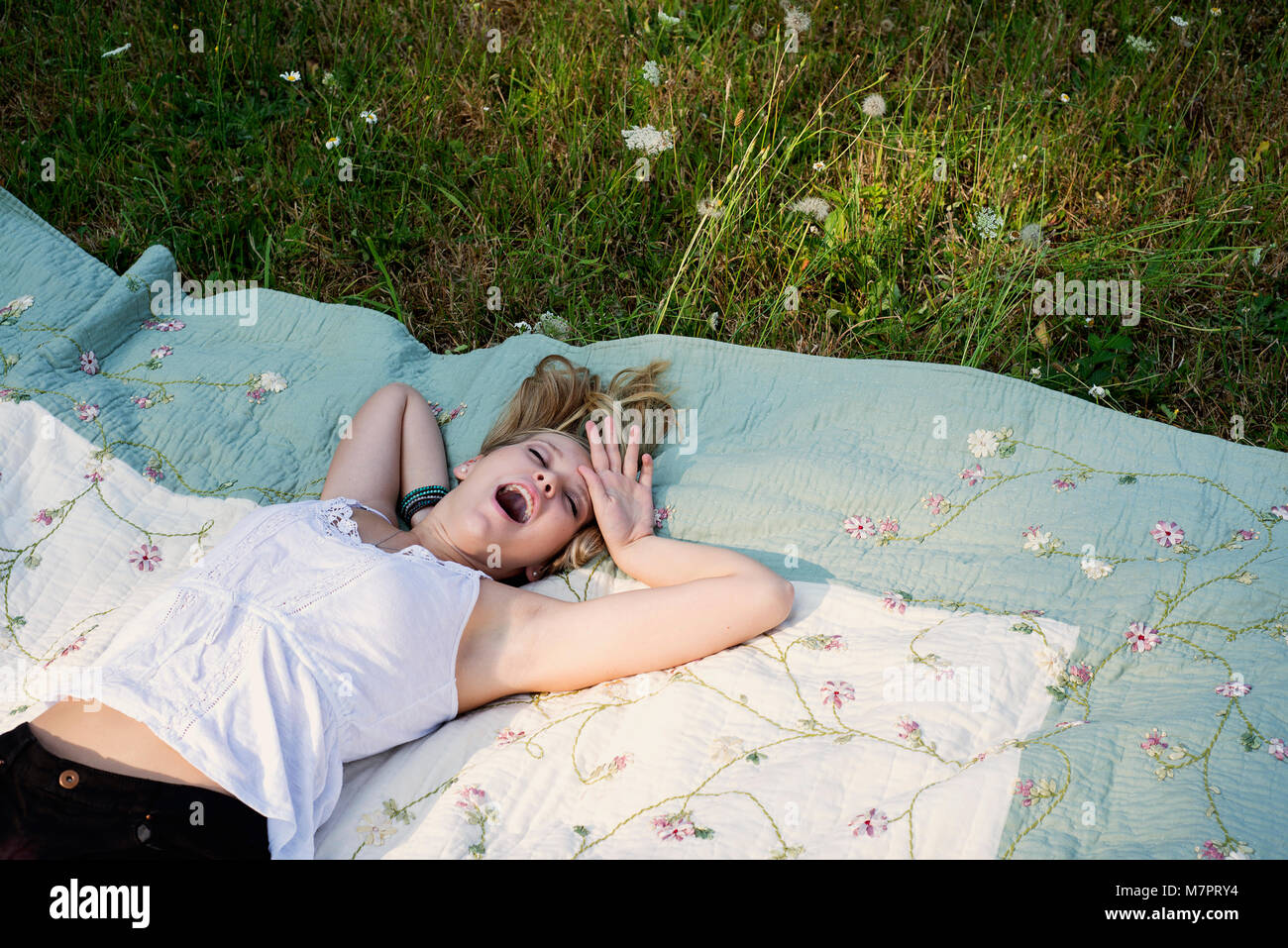 Teenaged Mädchen Gähnen im Gras Stockfoto