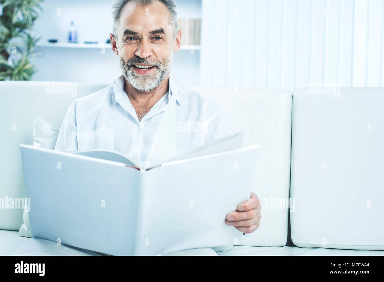 Geschäftsmann mit einem Magazin sitzen auf einem Sofa in hellen Büro. Stockfoto