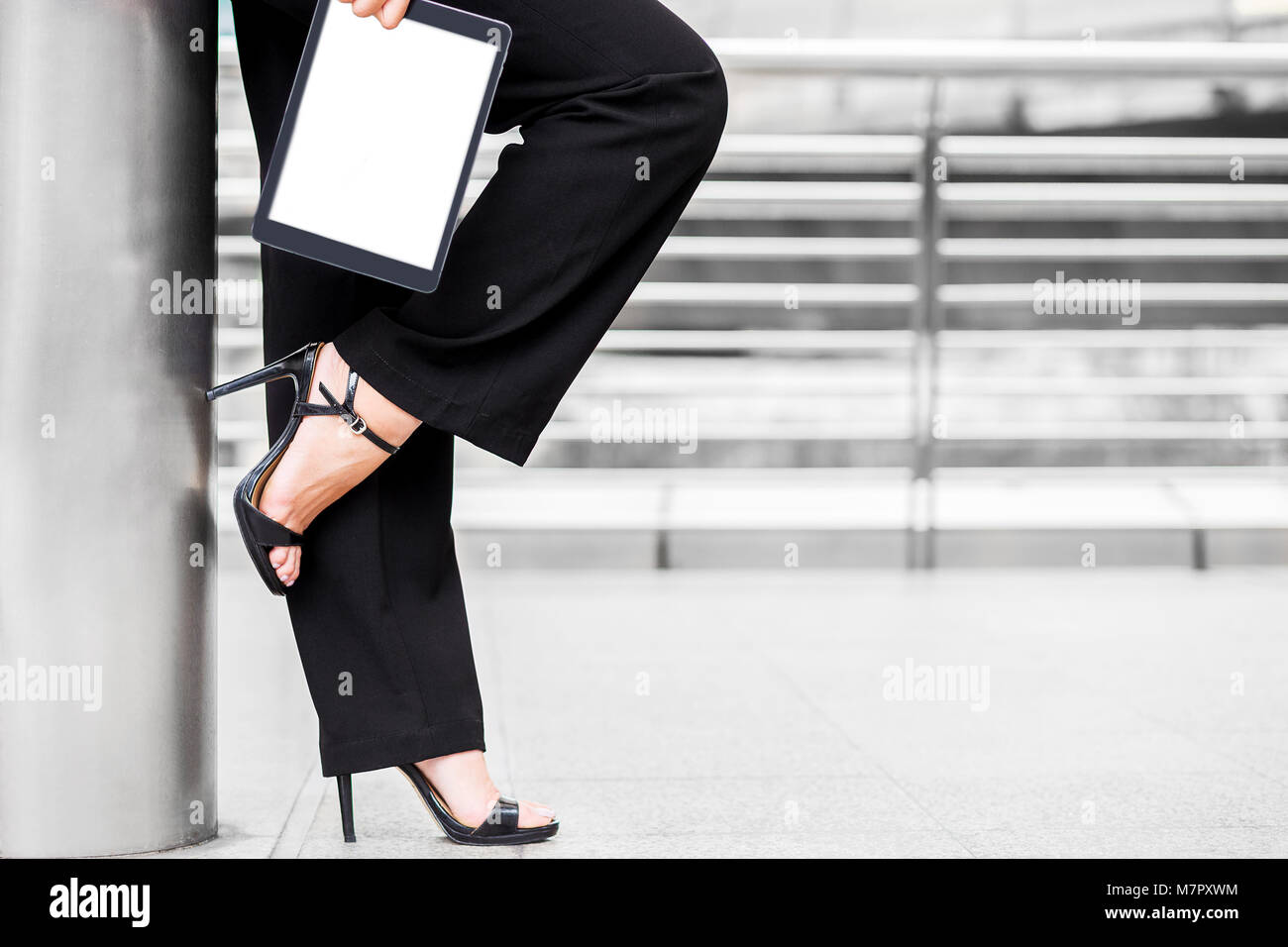 Business Frau tragen High Heel und halten Sie die Tablette lean gegen die Post für Ruhe und in der Innenstadt von Center von Business relax Zone Stockfoto