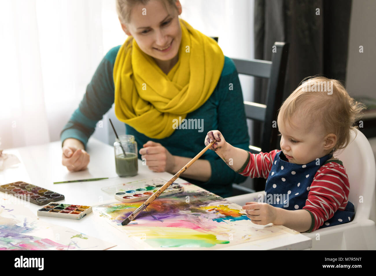 Die Mutter ihrer kleinen Tochter wie mit Wasserfarben malen Stockfoto