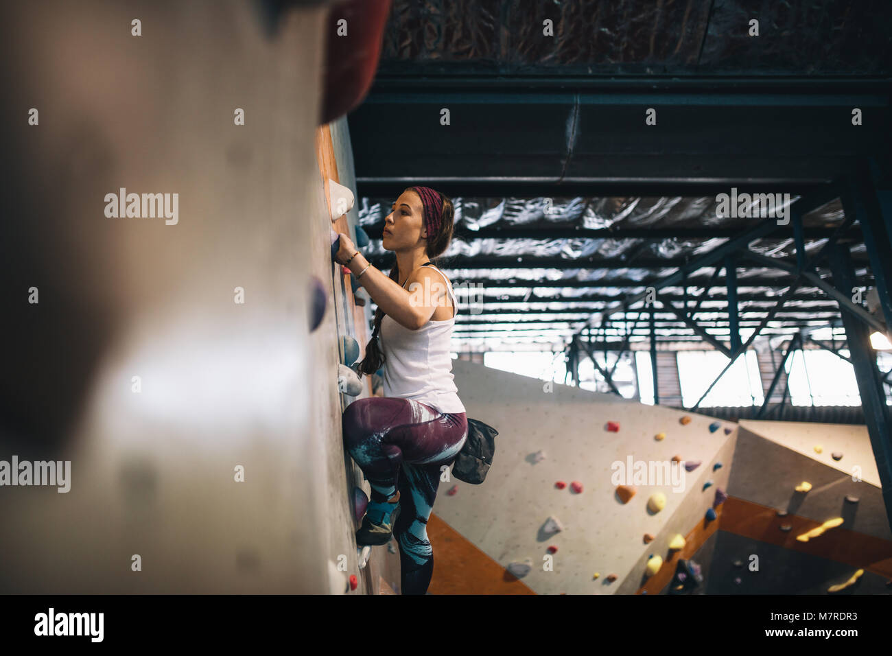 Frau Bouldern in einer Kletterhalle. Kletterer üben Klettern in einer Kletterhalle. Stockfoto