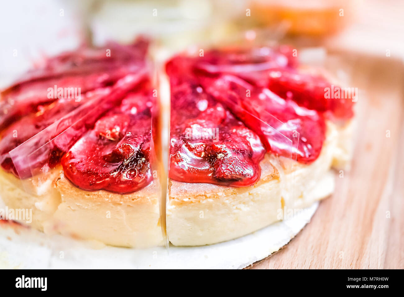 Nahaufnahme der Erdbeere gebackene Käsetorte Kuchen Schichten mit Sirup, Detail, Textur von roten Beeren auf Holztisch ganze Stockfoto