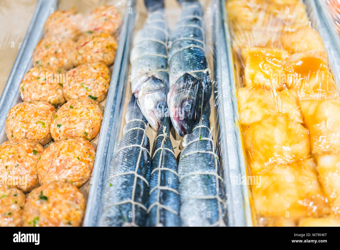 Nahaufnahme von viele Heringe Fisch ganz Augen Plastik eingewickelt, Kuchen Burger in Seafood Market Anzeige Stockfoto