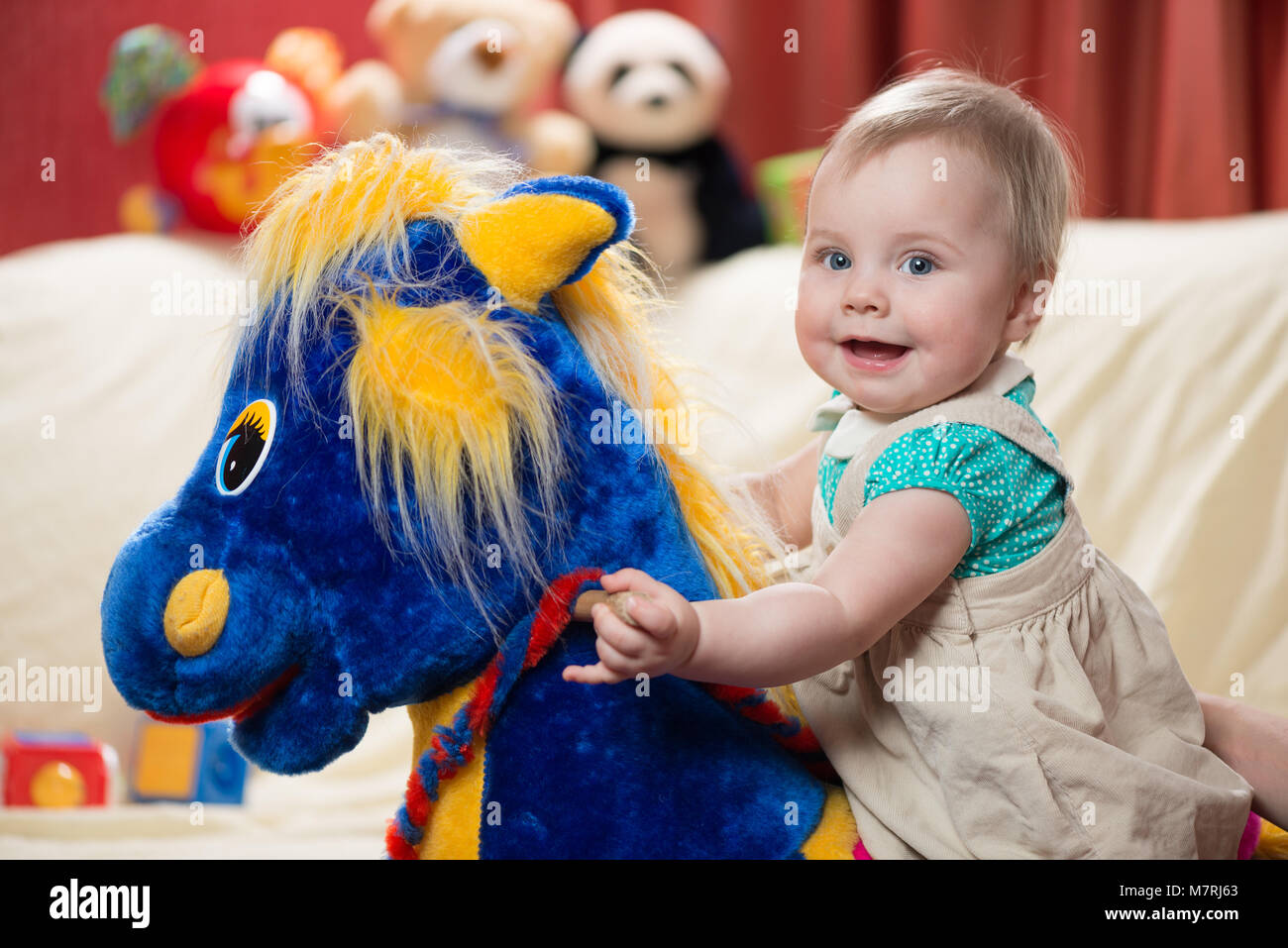 10 Monate altes Baby Mädchen Schwingen auf einem schaukelpferd Spielzeug Stockfoto
