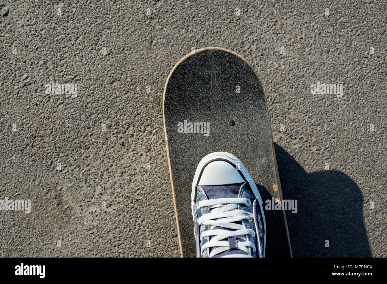 Skateboard mit Bein auf dem Starten auf Asphalt Stockfoto