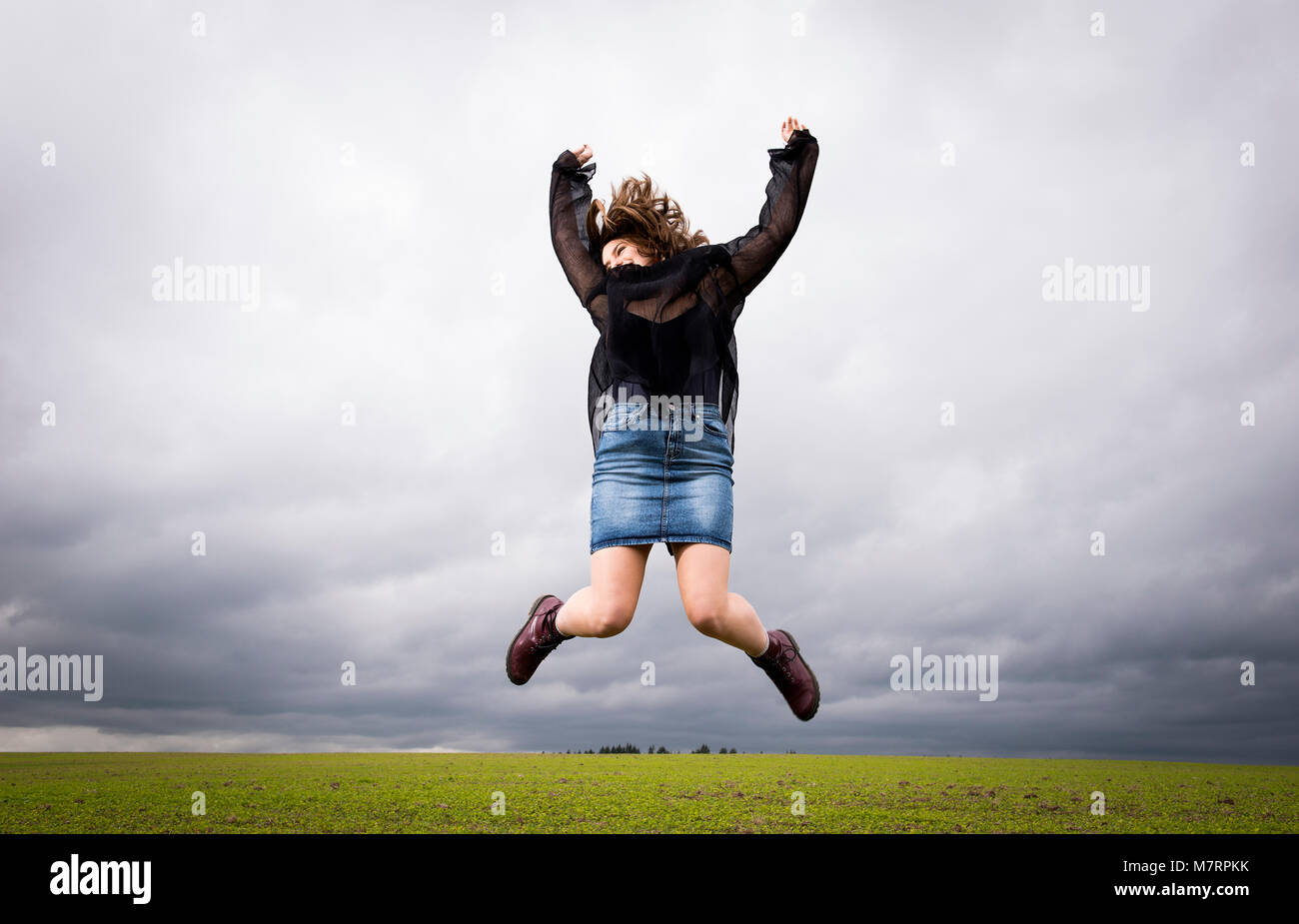 Ein Mädchen im Teenageralter springen in einem Feld. Stockfoto