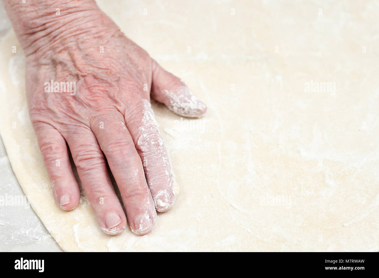 Altersstar Frau Hand gefärbt mit Mehl streichelte die gestreckte Teig, close-up Stockfoto