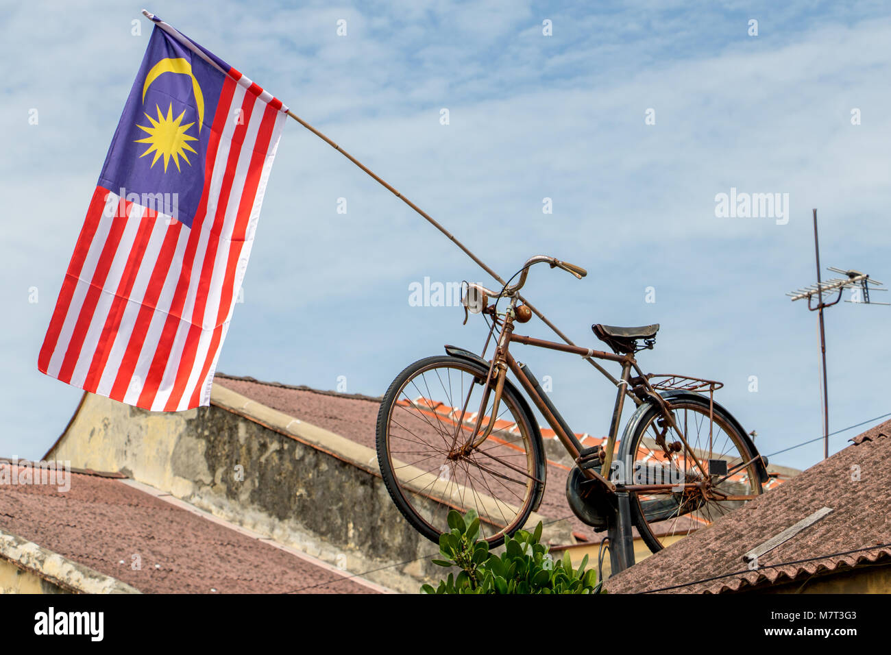 Die Malaysia Flagge hängt an einer Stange auf dem Dach mit einem alten retro Fahrrad, Penang montiert. Stockfoto