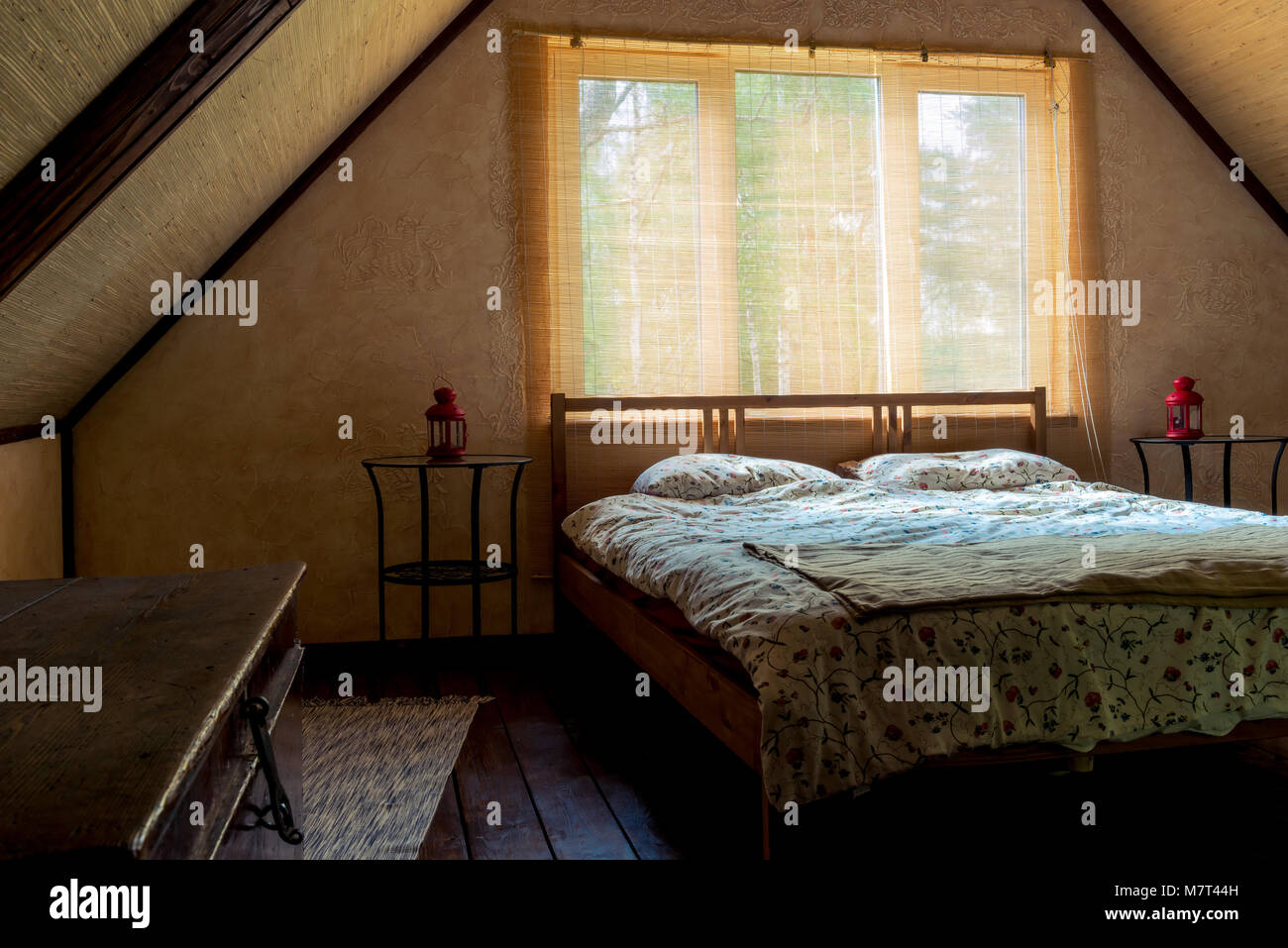 Bett in der Nähe ein Fenster in einem Zimmer auf der obersten Etage eines Hauses, unter einem Dach Stockfoto