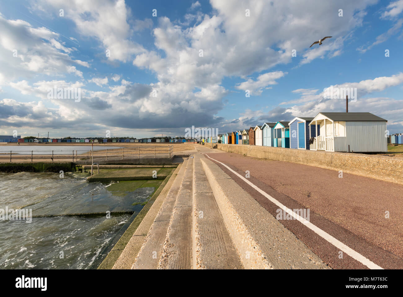 Helles Licht und große Wolken über dem Strand Hütten am Brightlingsea, Essex. Stockfoto