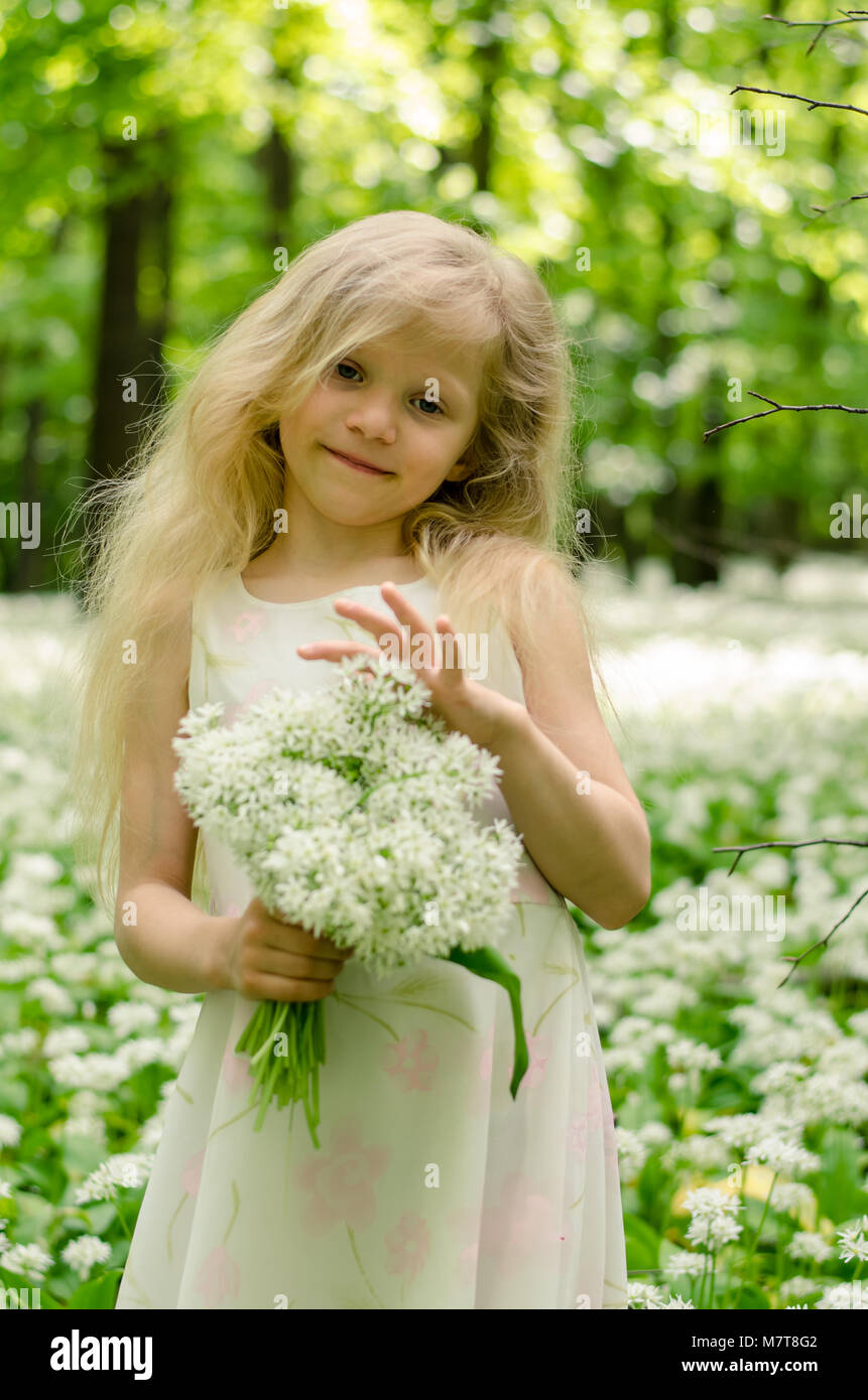 Schöne Mädchen Märchen mit langen blonden Haaren Holding ein Bündel weißer Bärlauch blüht im Frühjahr Wald Stockfoto