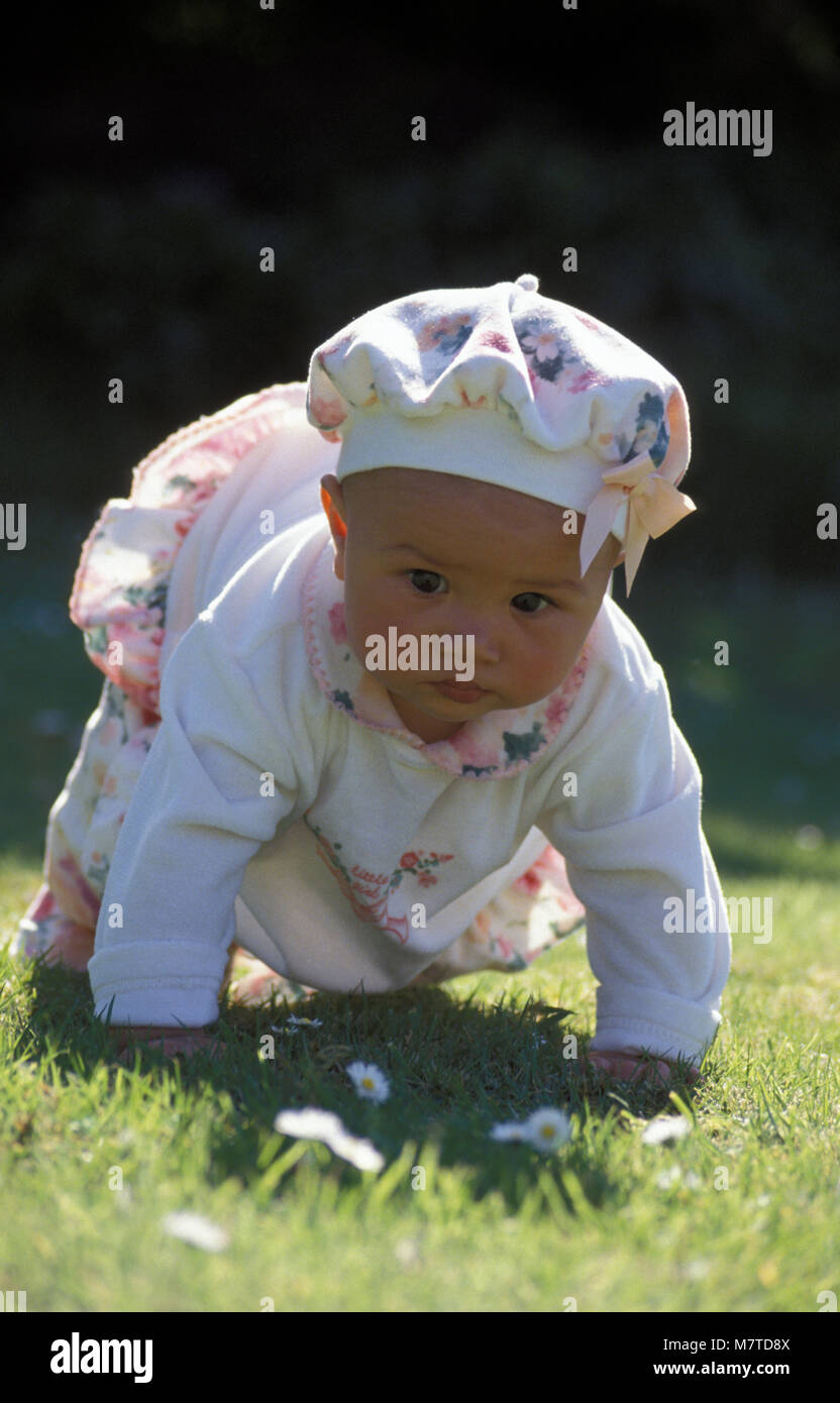 Multikulturelle baby girl Kriechen im Garten an einem sonnigen Tag Stockfoto