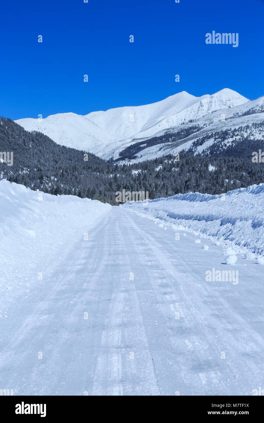 Straße durch tiefen Schnee im Winter gepflügt auf kleinschmidt flach unter den Bergen in der Nähe von Ovando, Montana Stockfoto