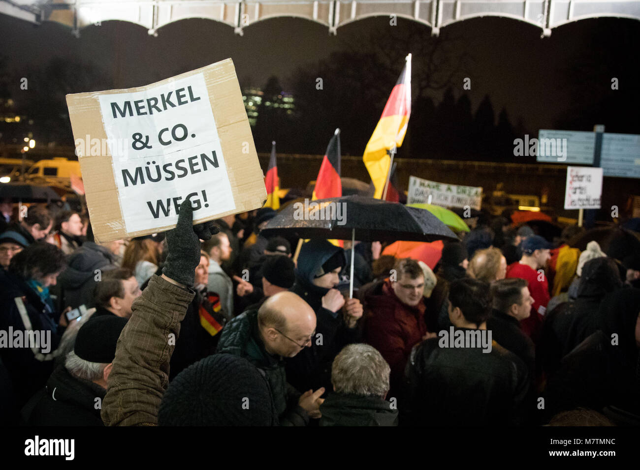 12 März 2018, Deutschland, Hamburg: die Teilnehmer der Protestbewegung Ereignis 'MErkel muss weg' (lit. Merkel hat zu gehen) am Dammtor Platz vor dem Bahnhof Dammtor demonstrieren. Einer der Teilnehmer hält ein Schild mit der Aufschrift 'MErkel & Co muessen weg!" (Lit. Merkel & Co zu bekommen). Mehrere hundert gegen Demonstranten versuchen, die Kundgebung zu stören. Foto: Christian Charisius/dpa Stockfoto