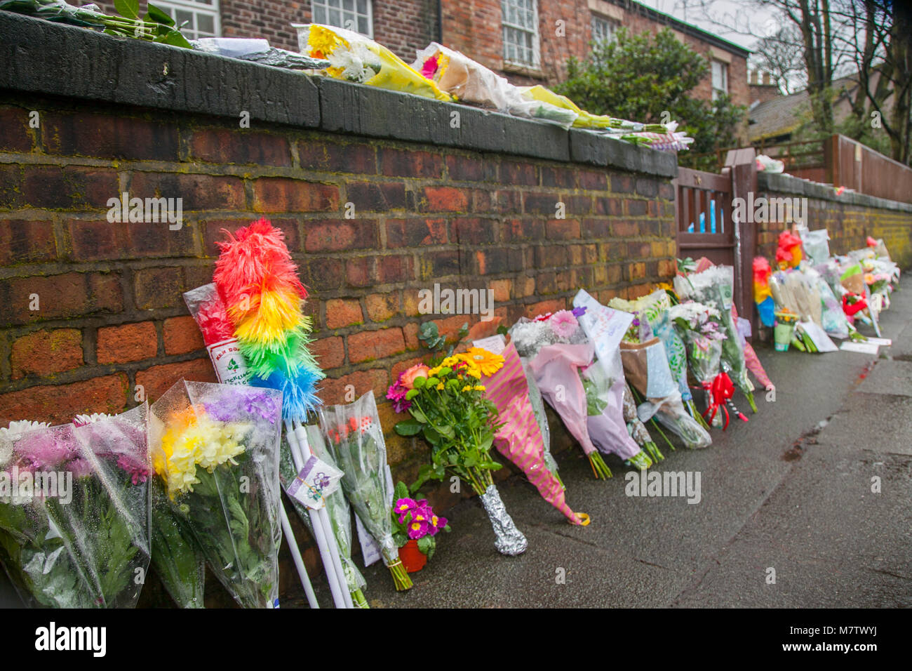 Knotty Esche, Liverpool, Großbritannien. 13. März, 2018. Floral Tribute weiter außerhalb Ken Dodds Liverpool home als Bewohner der Stadt Ehre ein großer Komiker platziert zu werden. Blumen und Staubwedel, (ticking Sticks) haben außerhalb des Hauses in einer langen Linie, die entlang der Wand an der Grenze zum Grundstück platziert. Sir Ken Dodd starb im Alter von 90, mit Ehrungen aus aller Welt für die Viel-Komiker geliebt zu gießen. Kredit MediaWorldImages/AlamyLiveNews. Stockfoto
