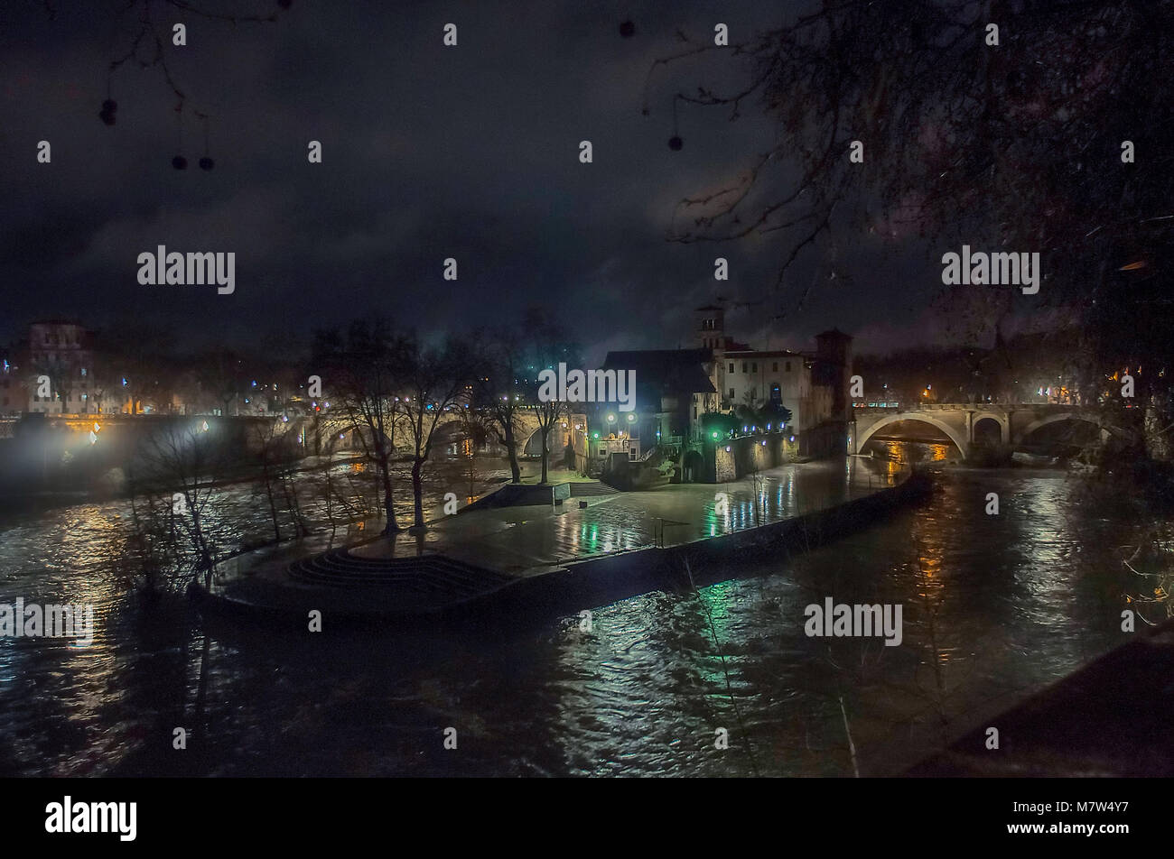 Tiberinsel auf dem Tiber in Rom bei Nacht mit bunten Reflexionen auf dem Wasser, Isola Tiberina Stockfoto