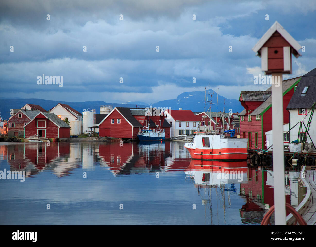 Waterfront Holzhäuser und Fischerboote im Wasser spiegeln im Hafen von Kalvaag - einem kleinen Dorf in Bremanger Norwegen Stockfoto