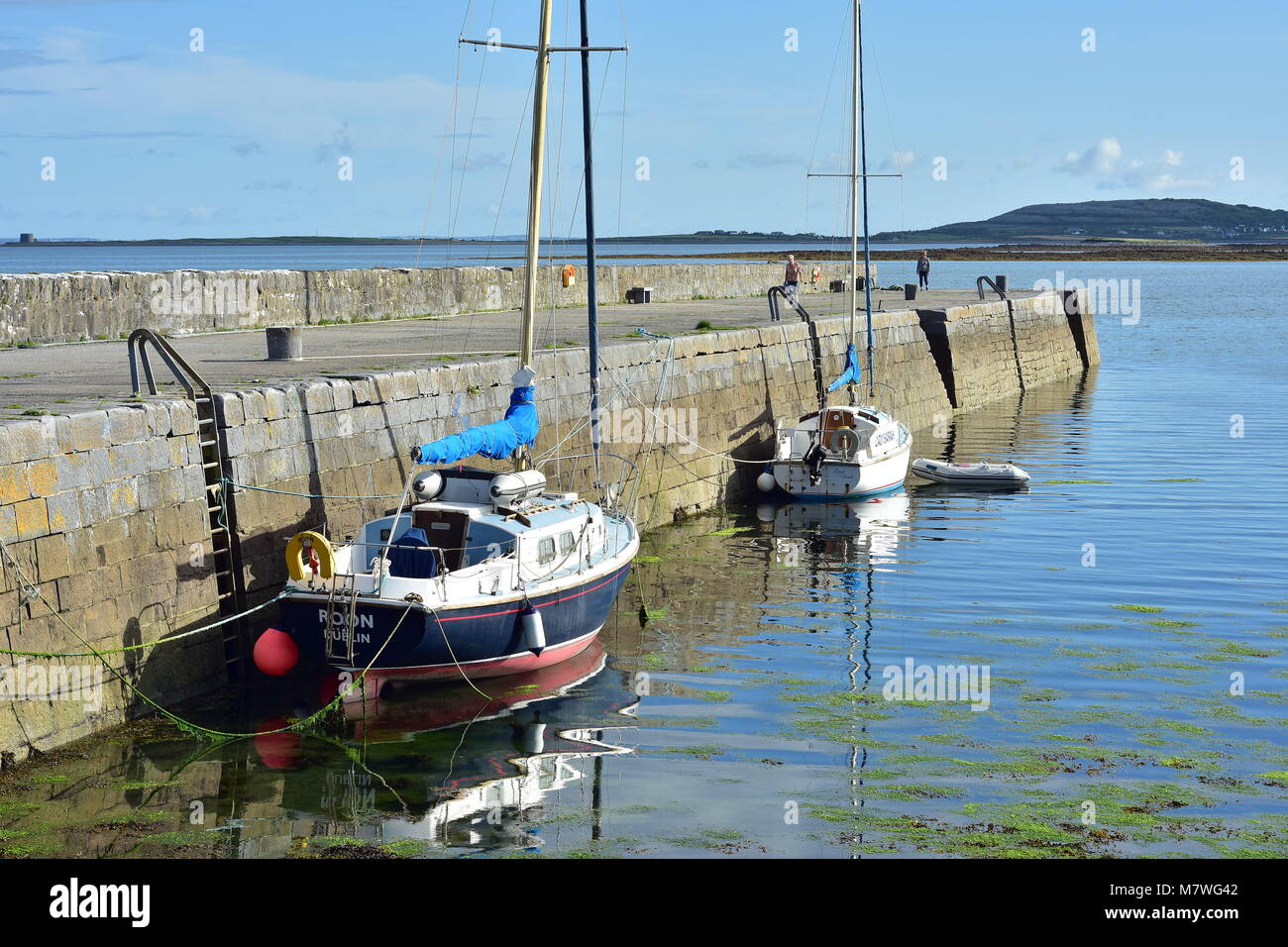 Ruhiges Meer Oberfläche um Stein Pier mit zwei Segelboote auf Atlantischen Küste Irlands gebunden. Stockfoto