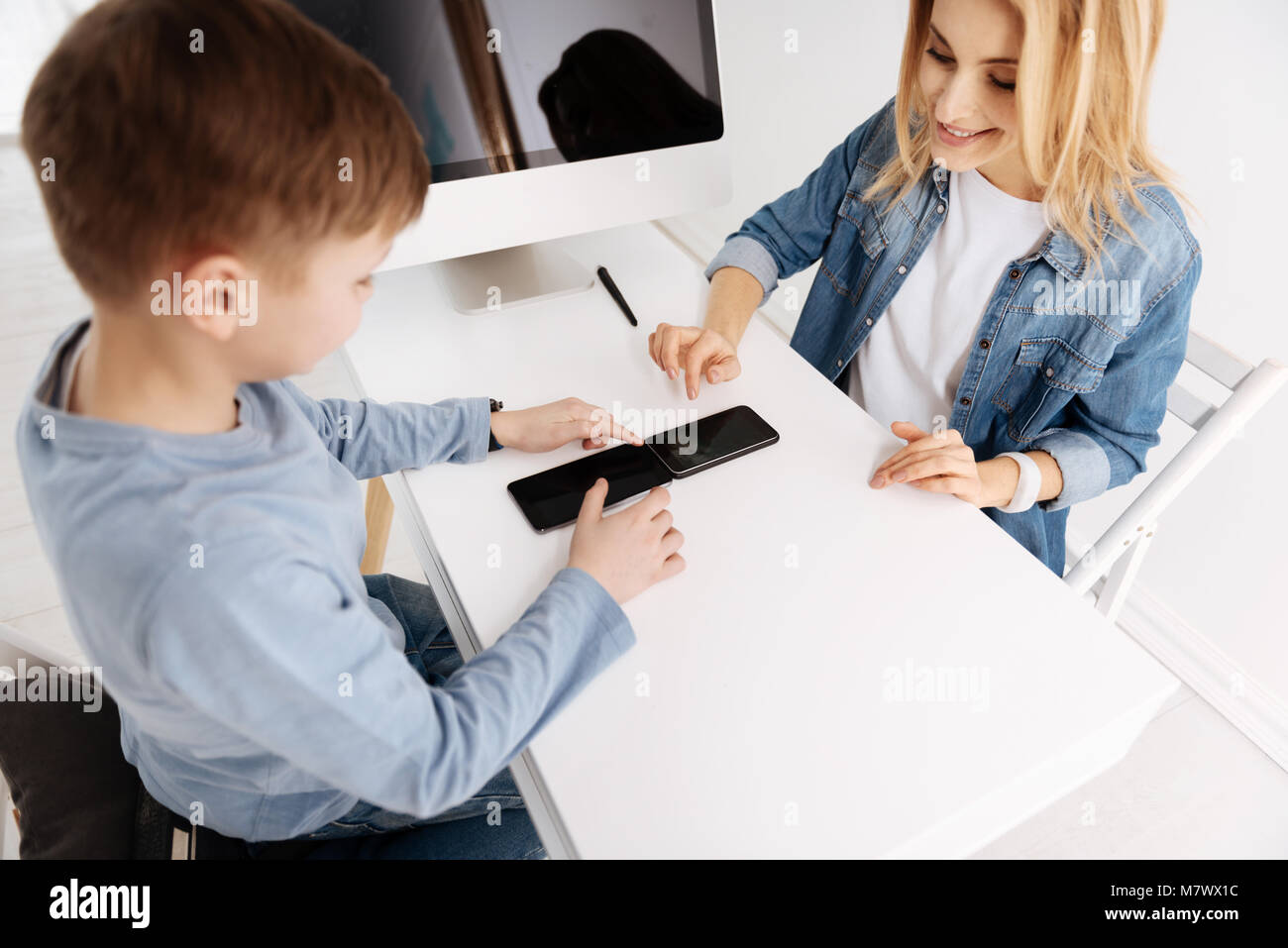 Positive fröhliche Mutter und über ihre gadgets Sohn Stockfoto